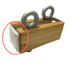 Wooden block with metal rings on top, highlighted by a red circle.